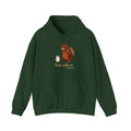 Bear With Me penguin hoodie in Forest Green: A small penguin with a walking stick stands beside a big brown bear wearing…