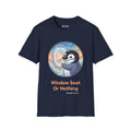 Window Seat penguin T-shirt in Navy: A cartoon chinstrap penguin beside a round airplane window full of peach and blue…