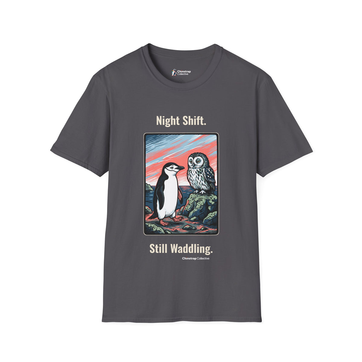 Still Waddling penguin T-shirt in Charcoal: The art shows the chinstrap penguin on the rocky shore at dawn, trading a…