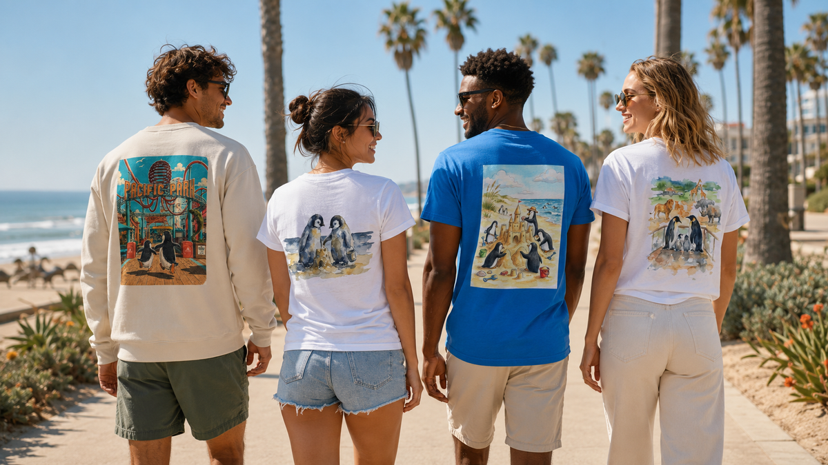 Four friends walking toward the beach under palm trees, wearing penguin-print T-shirts and a sweatshirt