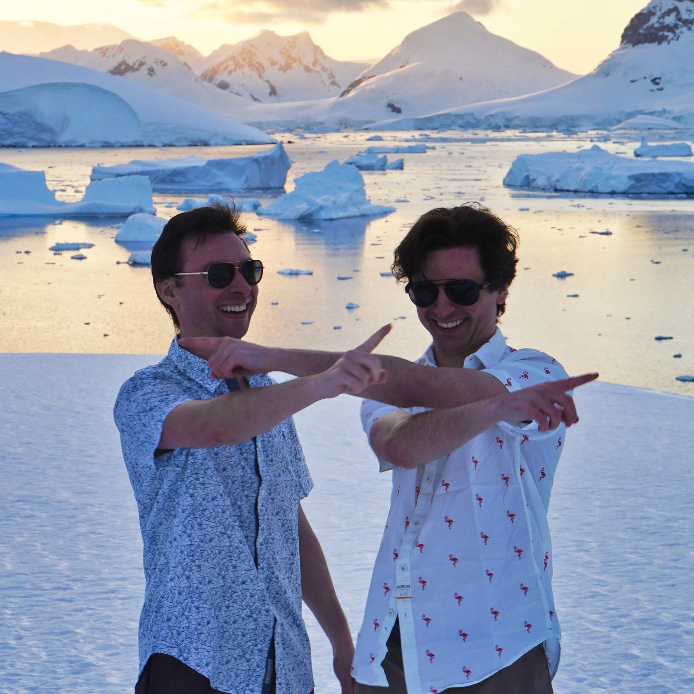 Founders Gabi and Dani pointing and laughing in front of icebergs and snowy peaks