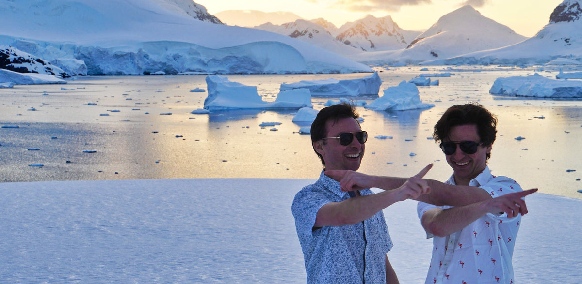 Founders Gabi and Dani pointing and laughing in front of icebergs and snowy peaks